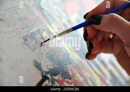 Malen nach Zahlen. Die Hand hält einen Pinsel und malt. Stockfoto