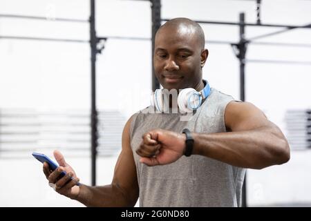 Porträt eines afroamerikanischen männlichen Sportlers, der seine Armbanduhr anschaut. Konzept der Technik im Sport. Selektiver Fokus. Stockfoto