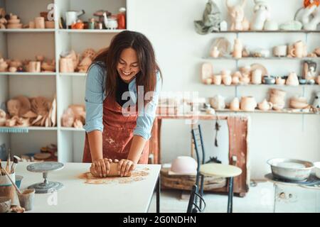 Fröhliche junge Frau, die in der Töpferwerkstatt arbeitet Stockfoto