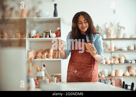 Schöne fröhliche Frau, die in der Töpferwerkstatt arbeitet Stockfoto