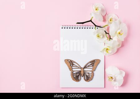 Öffnen Sie Notizbuch und Orchideenblumen auf einem rosa Hintergrund. Speicherplatz kopieren. Stockfoto
