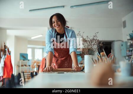 Lächelnde junge Frau, die in der Töpferwerkstatt arbeitet Stockfoto