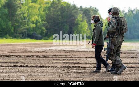 Münster, Deutschland. Juni 2021. Verteidigungsministerin Annegret Kramp-Karrenbauer (l., CDU) geht mit Christian Freuding (2. V.l.), Kommandant der Panzertrainingsbrigade 9, und einem Soldaten durch das Trainingsgelände. Bei der rund 5,000 Mann starken Armee-Brigade in Niedersachsen konnte sich der Minister persönlich ein Bild von den Fähigkeiten der Panzertrainingsbrigade 9 machen. Quelle: Philipp Schulze/dpa/Alamy Live News Stockfoto