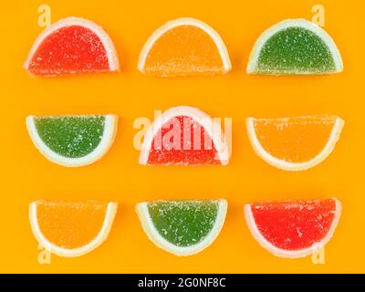 Bunte Marmelade Zitrusscheiben in Zucker auf orangefarbenem Hintergrund. Stockfoto