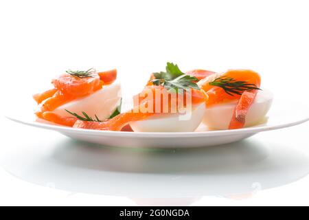 Hälften gekochter Eier mit Stücken gesalzenem Lachs isoliert Auf weißem Hintergrund Stockfoto