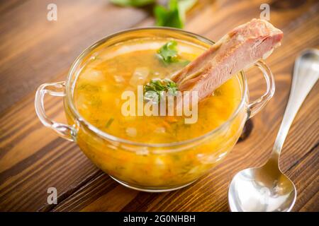 Gekochte Erbsensuppe mit auf einem Teller geräucherten Rippchen Stockfoto