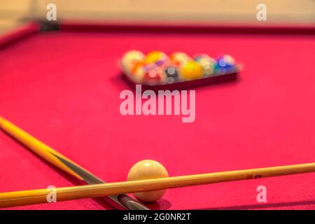 Queuesticks und Billardkugeln auf einem roten Billardtisch Stockfoto