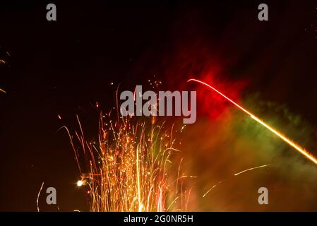 Nahaufnahme aus der Nähe eines niedrigen Winkels von einem wunderschönen, farbenfrohen Feuerwerk, das nachts am dunklen Himmel explodiert Stockfoto
