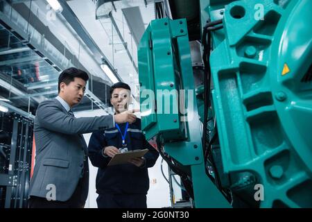 Technisches Personal mit führenden Inspektionsmaschinen im Werk Stockfoto