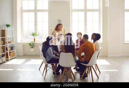 Personen, die an einer Gruppentherapie zur Ausbildung sozialer Fähigkeiten im hellen Büro teilnehmen Stockfoto