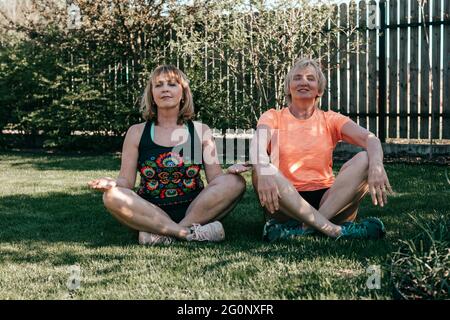Lifestyle-Porträt älterer Frauen während des Yoga in der Natur. Meditation von zwei Frauen in Lotusposition im Freien Stockfoto
