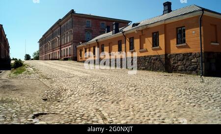 Klassische Gebäude aus dem 19. Jahrhundert entlang einer gepflasterten Straße, ehemalige Garnisonskaserne, in der Festung Suomenlinna, Helsinki, Finnland Stockfoto