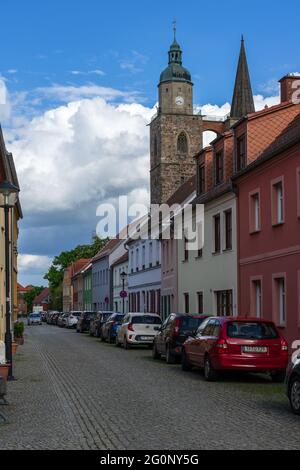 JUETERBOG, DEUTSCHLAND - 23. MAI 2021: Straßen der Altstadt. Im Hintergrund die Kirche des Hl. Nikolaus. Juterbog, Deutschland. Stockfoto