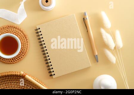 Basteln Sie Papier-Notizblock und Stift mit getrockneten Blumen auf einem beigen Tisch. Eleganter femininer Arbeitsplatz, Schreibtisch im Home Office. Flach liegend, Draufsicht, Kopierbereich. Stockfoto