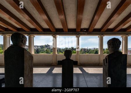 Athen, Attika, Griechenland. Alte Statuen in männlicher Gestalt an der Stoa von Attalus bewundern den Blick auf die archäologische Stätte der antiken Agora Stockfoto