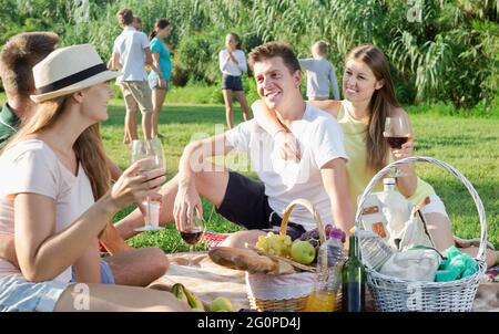 Glückliche junge Leute beim Picknick im Park und spielende Kinder Stockfoto