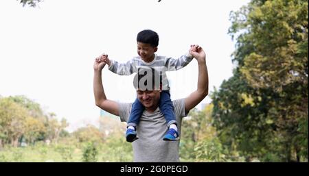 Kleiner asiatischer Junge saß auf den Schultern des Vaters im Gartenpark Stockfoto