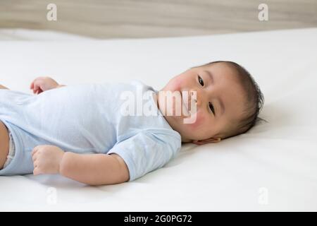 Asiatischer Baby Junge lag auf dem Bett und hatte einen roten Ausschlag auf dem Gesicht, Haut gemeinsame Ausschläge in neugeborenen Konzept Stockfoto