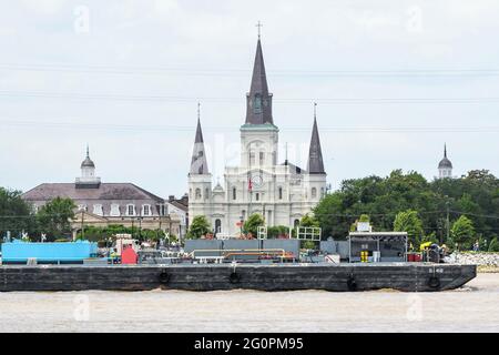 St. Louis Cathedral, das Cabildo, die Presbytere und ein vorbeifahrende Lastkahn vom Westufer des Mississippi River Stockfoto