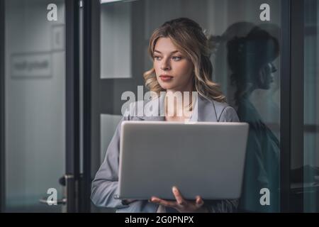 Junge Geschäftsfrau, die mit einem offenen Laptop steht Stockfoto