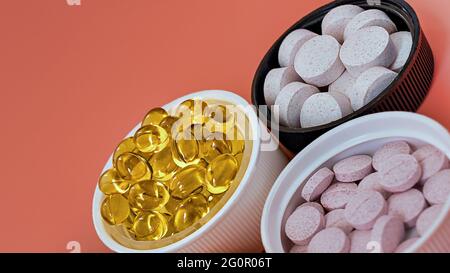 Nahaufnahme von biologisch aktiven Multivitamin-Nahrungsergänzungsmitteln auf korallenfarbenem Hintergrund. Psychisches Wohlbefinden und persönliches Gesundheitskonzept Stockfoto