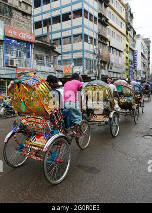 Bunte Rikschas durchstreifen die Straßen von Dhaka, Bangladesch. Stockfoto