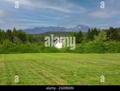 Haus im Farmstil mit den kaskadierenden Bergen im Hintergrund. Stockfoto