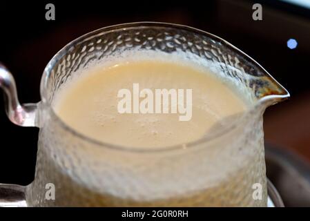 Die gekochte Milch in einem Glasgefäß mit dem Griff und Auslauf Stockfoto