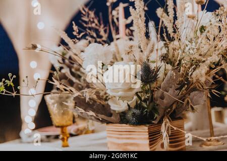 Blumenstrauß im Boho-Stil, schmücken die festliche Tafel, getrocknete Blumen, weiße Rosen, floristisches Konzept. Stockfoto