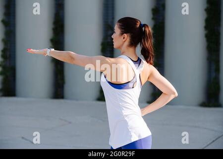 Fit Frau Training auf einem Betonpflaster. Über Stützen. In blauer dehnbarer Yogahose. Seitenansicht. Stockfoto