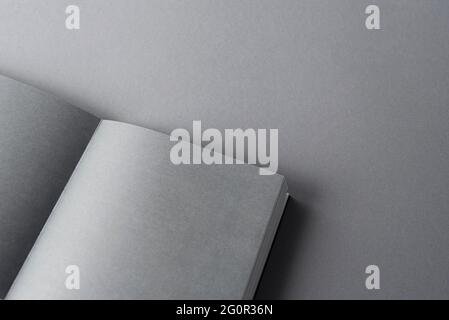Buchmockup, geöffnetes Buch mit leeren grauen Blättern auf Papieroberfläche. Draufsicht, Platz für Text, flach liegend Stockfoto