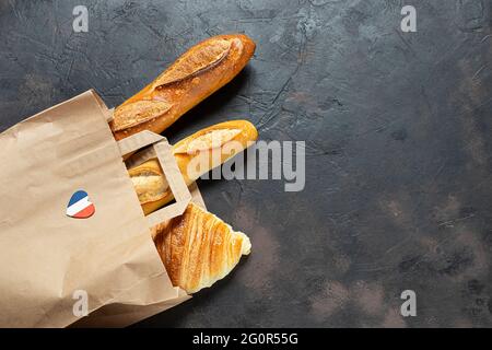 Französisches Schneckenbrötchen, Croissants und Baguette in einer umweltfreundlichen Papiertüte auf dunklem Hintergrund, Zero Waste Konzept, Draufsicht mit Kopierraum Stockfoto