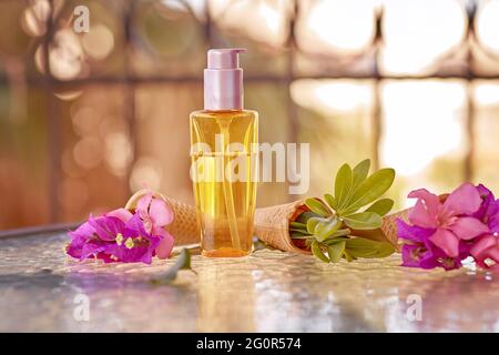 Surreal rosa Bougainvillea blüht in einem Eiskegel und imitierte Kosmetiköl Bottle Mock-Up. Natürliche Schönheitsprodukte. Öko-Creme, Serum, Hautpflege leere Flasche. Beauty-Produkte für den Sommer. Stockfoto