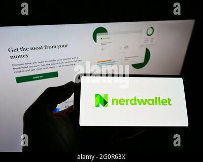 Person, die ein Mobiltelefon mit dem Logo des amerikanischen privaten Finanzunternehmens NerdWallet Inc. Auf dem Bildschirm vor der Webseite hält. Konzentrieren Sie sich auf die Telefonanzeige. Stockfoto