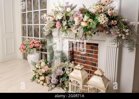 Stilvolles Interieur des Wohnzimmers mit Kunstblumen und Kamin Stockfoto