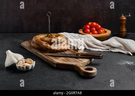Pferdefleischwurst mit Knoblauch auf Holzschneidebrett gerollt Stockfoto