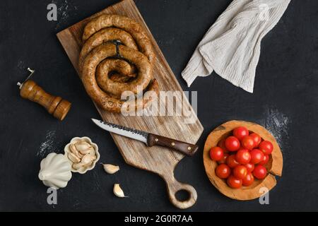 Pferdefleischwurst mit Knoblauch auf Holzschneidebrett gerollt Stockfoto
