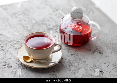 Beerentee in Glas Teekannen auf grauer Oberfläche Stockfoto
