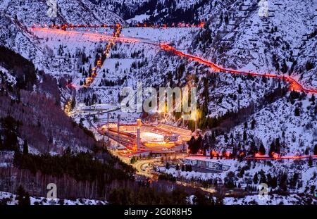 Almaty, Kasachstan - 19. Februar 2021: Medeo-Tal mit einem Schlammdamm und einer gleichnamigen Eislaufbahn in der Dämmerung Stockfoto