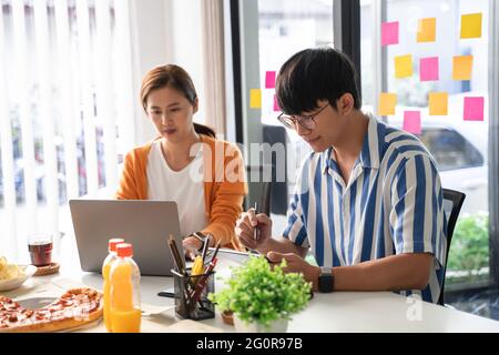 Die Mitarbeiter des Geschäftsteams besprechen die Arbeit und bereiten Pizza und Kartoffeln zu Chips zum gemeinsamen Essen in der Mittagspause für gute Beziehungen Im Büro Stockfoto