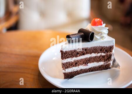 Nahaufnahme süße leckere dunkle Schokolade mit Creme und Erdbeergelee und Beerenmarmelade im Café, sehr frischer Kuchen, der aus dem Ofen gebacken und in Scheiben geschnitten wird Stockfoto