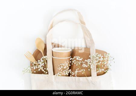 Öko Geschirr und Gypsophila Blumen in einer Einkaufstasche auf weißem Hintergrund. Stockfoto