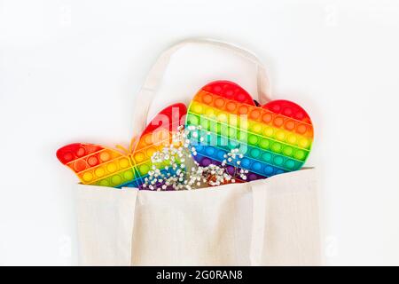 Spielzeug Pop it, einfache Dimple Regenbogenfarbe in einer Einkaufstasche auf weißem Hintergrund Stockfoto