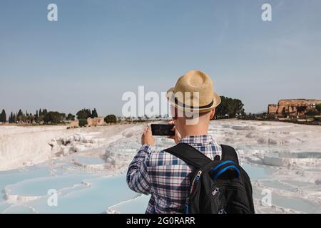 Junger männlicher Tourist in Strohhut, der in Pamukkale fotografiert. Stockfoto