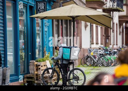 Seitenansicht des Deliveroo-Bikers, der vor dem Restaurant auf das Essen wartet Stockfoto