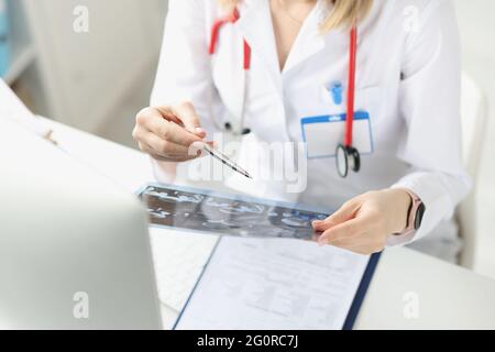 Der Arzt untersucht die Röntgenaufnahme des Patienten am Arbeitstisch Stockfoto