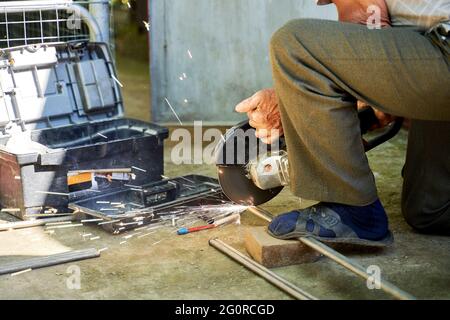 Ein Mann schneidet ein Titanrohr mit einem Schleifer Stockfoto
