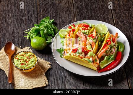 Shrimp Tacos mit Kohlsalat, Limette und Guacamole auf einem Teller Stockfoto