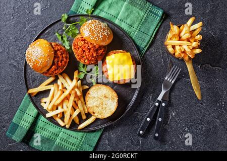 Hausgemachtes BBQ Sloppy Joe Sandwiches mit pommes auf einem schwarzen Teller, flach liegend, freier Platz Stockfoto