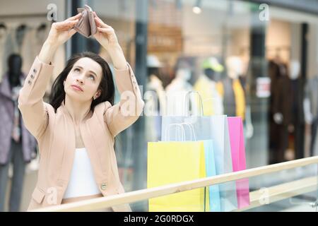 Junge Frau schaut in eine leere Brieftasche im Einkaufszentrum Stockfoto